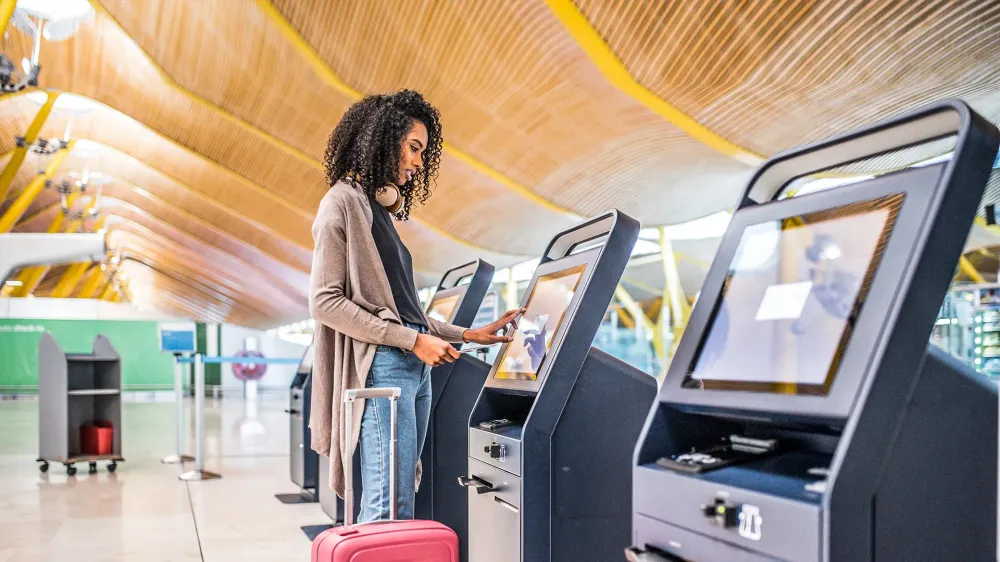 black woman using the check-in machine at the airport getting the boarding pass